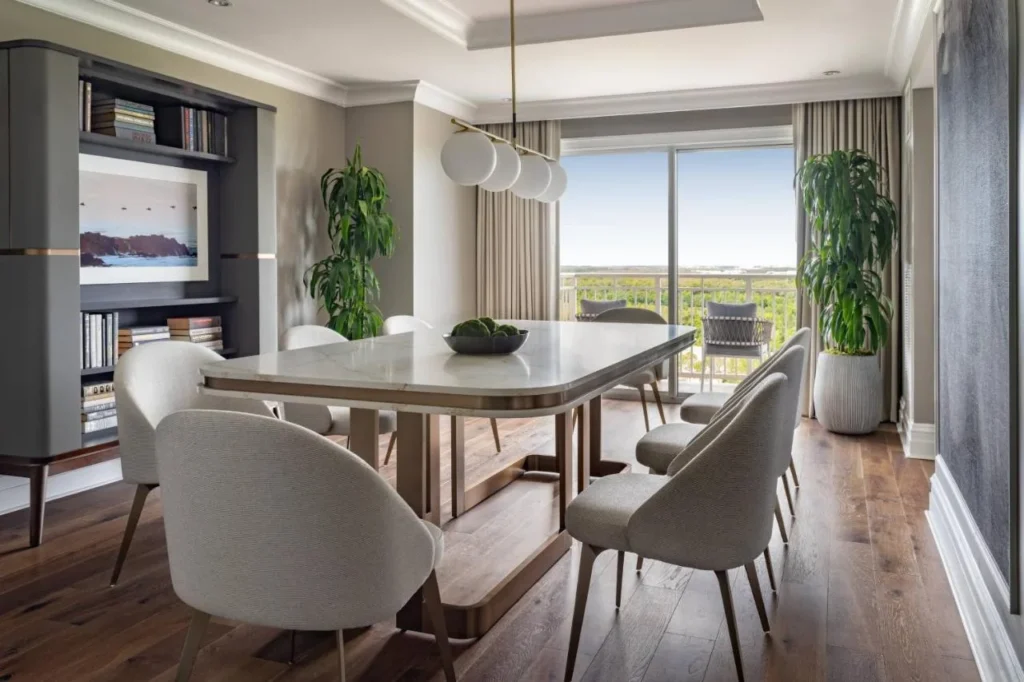 Suite comedor con mesa de mármol, estanterías y puertas de balcón en el Ritz-Carlton Orlando Grande Lakes