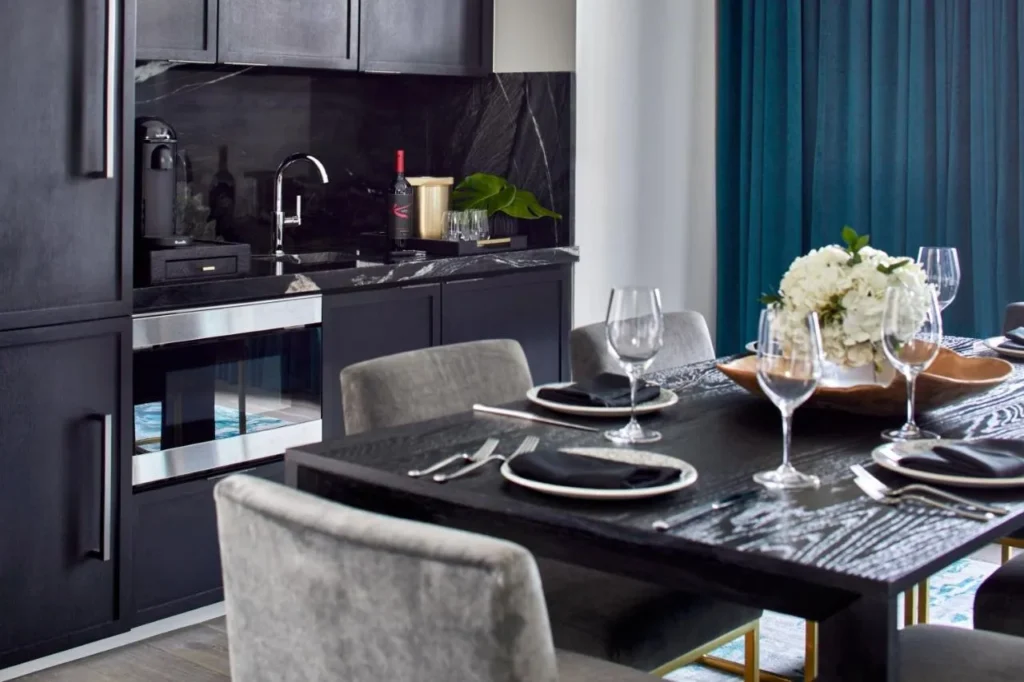 Suite dining table set for guests beside a dark marble kitchenette at Hotel Beauden