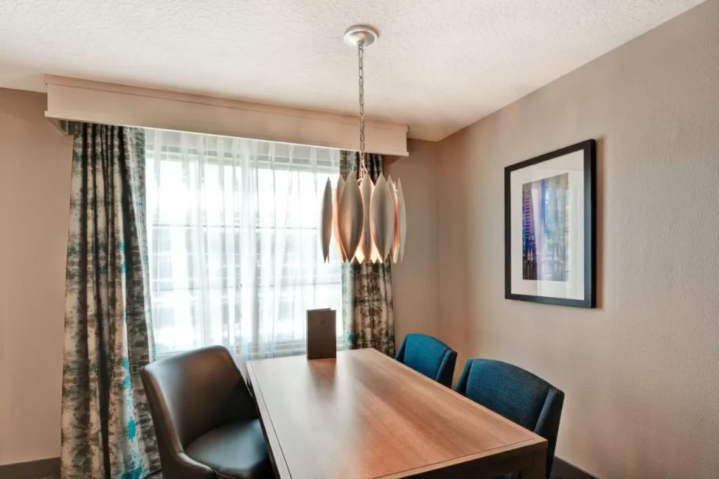 Suite dining table with blue chairs and pendant lamp at Embassy Suites Orlando Downtown