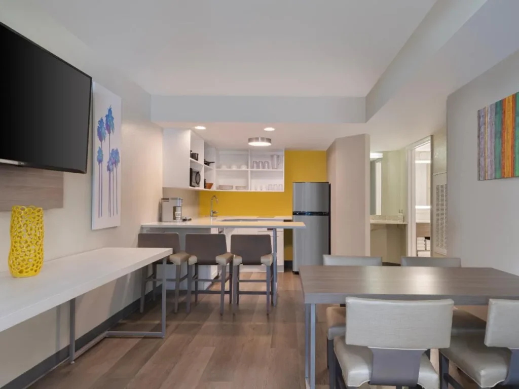 Suite kitchen with breakfast bar, refrigerator and dining table at Holiday Inn Resort Orlando Suites