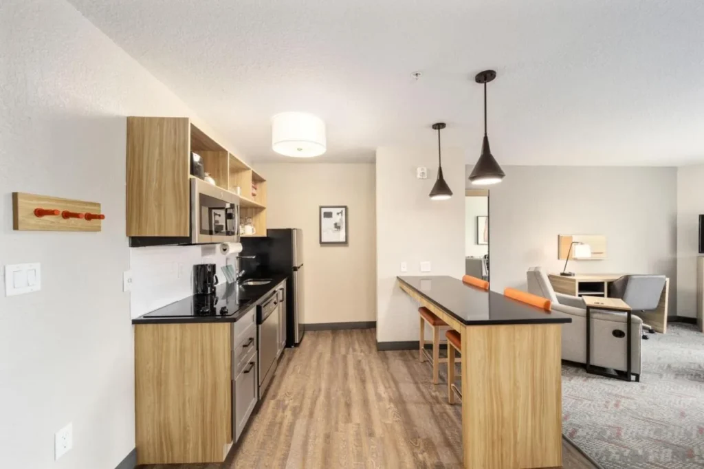Cocina suite con barra de desayuno, taburetes y sala de estar en Candlewood Suites Ocala I-75