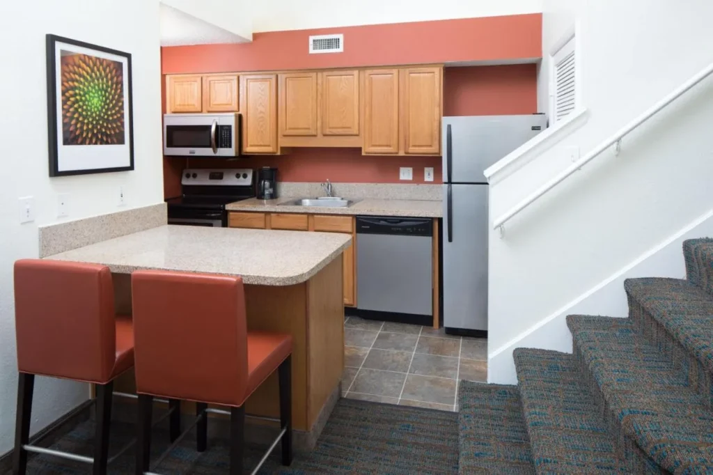 Suite de cocina con barra americana, estufa, lavavajillas y una escalera en el Residence Inn Altamonte Springs