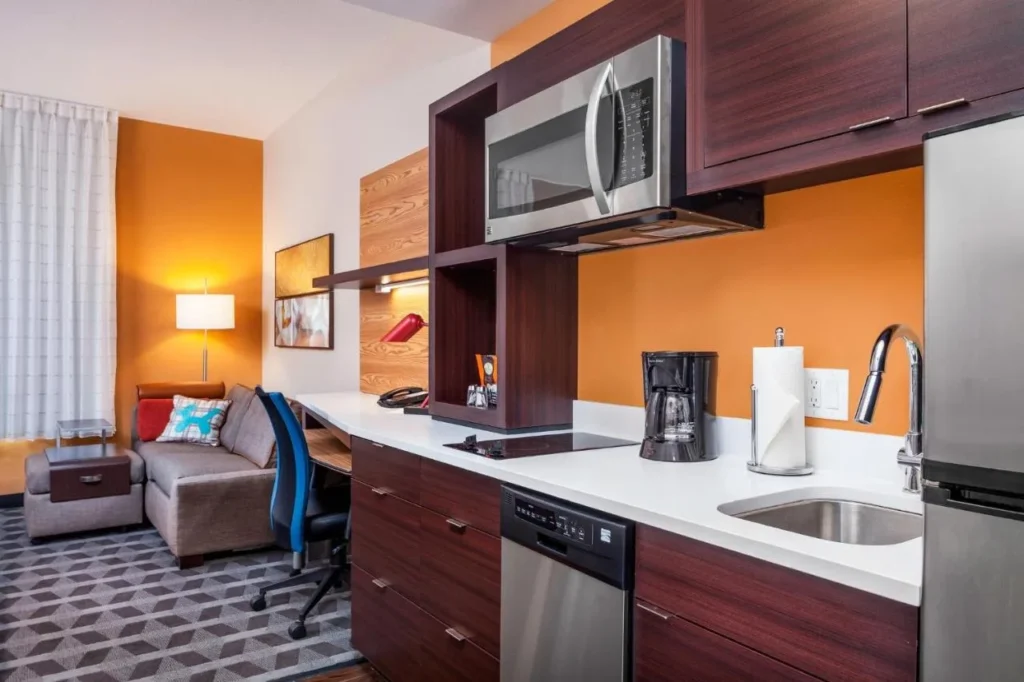 Cocina peque&ntilde;a con placa de cocina, lavavajillas, microondas y sof&aacute; en TownePlace Suites Altamonte Springs