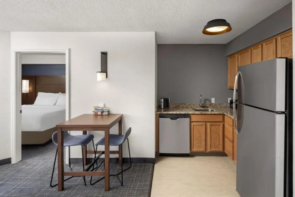 Suite de cocina con lavavajillas, nevera de tamaño completo y mesa de comedor en el Residence Inn Orlando East/UCF Área