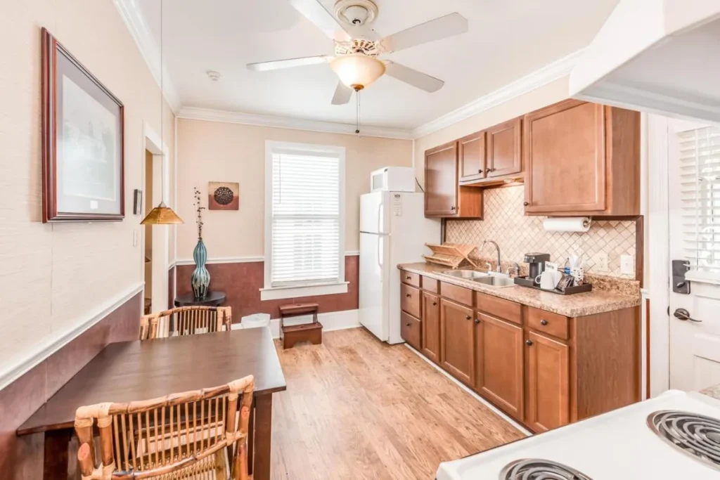 Suite kitchen with fridge, stove, microwave and small dining table at The Heirloom Inn