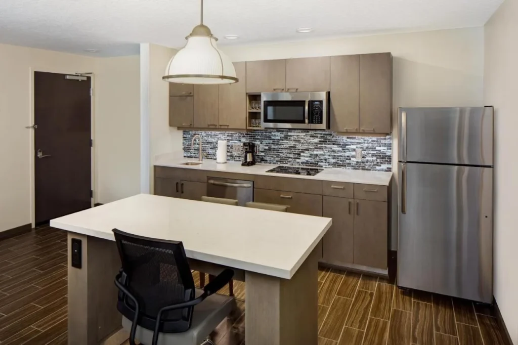 Cocina suite con nevera de tama&ntilde;o completo, placa de cocina, microondas y mesa de isla en Hyatt House frente a Universal