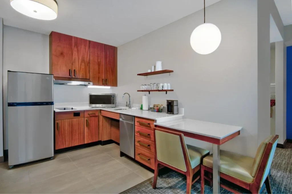 Cocina suite con refrigerador grande, placa de cocina, lavavajillas y mesa de comedor en el Residence Inn Flamingo Crossings