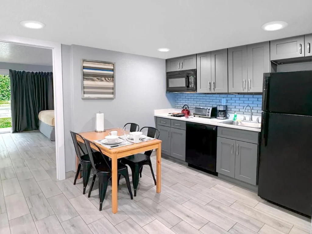 Cocina suite con refrigerador de tamaño completo, microondas, gabinetes y mesa de comedor en Celebration Suites