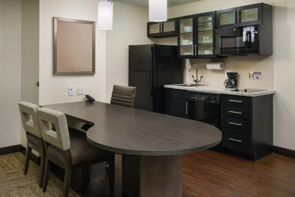 Suite de cocina con nevera, microondas, lavavajillas y mesa de comedor en Candlewood Suites Lake Buena Vista