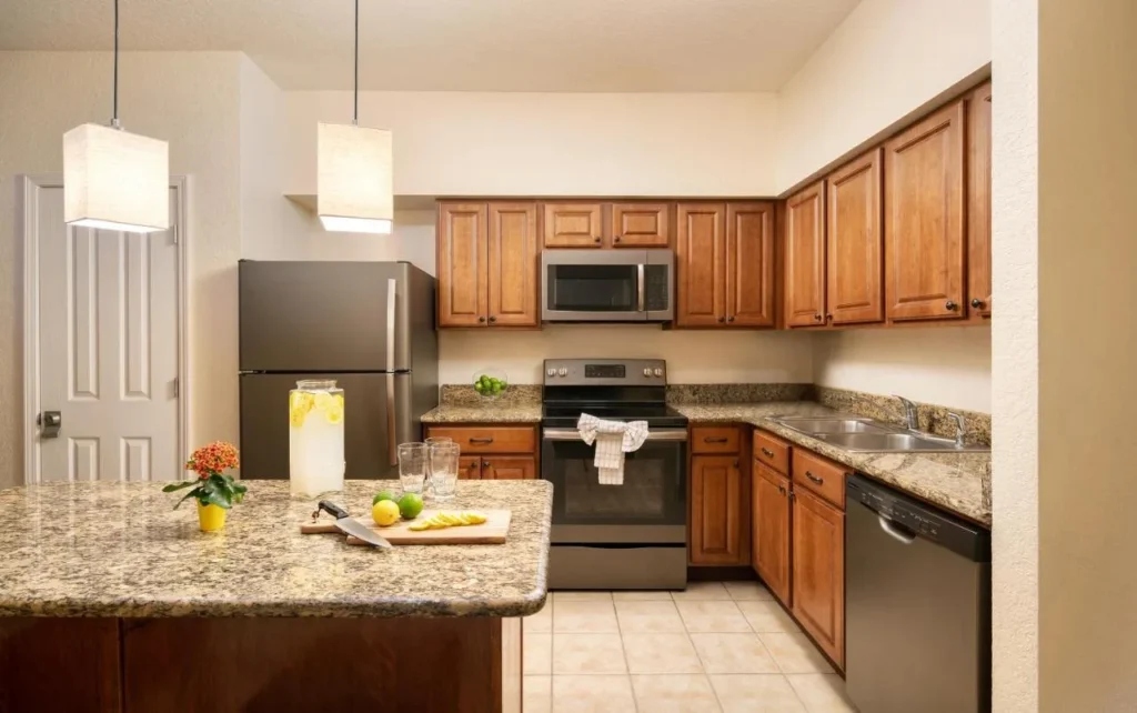 Cocina suite con gabinetes de madera, isla de granito y electrodom&eacute;sticos de acero inoxidable en Floridays Resort Orlando