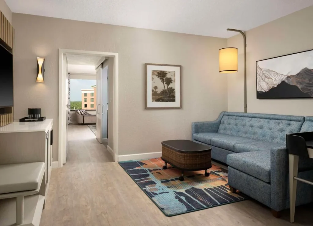 Suite living area with a blue sofa and open bedroom door at Caribe Royale Orlando