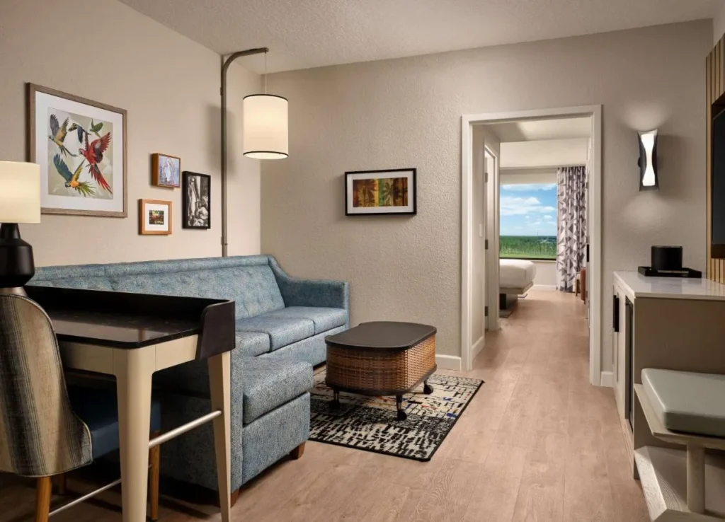 Suite con un sof&aacute; azul, escritorio y el dormitorio m&aacute;s all&aacute; en Caribe Royale Orlando