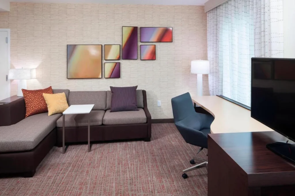 Suite living area with a sectional sofa, desk and TV at Residence Inn Near Universal Orlando