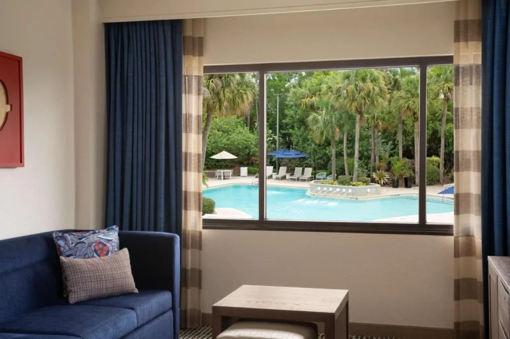 Suite con un sof&aacute; y una ventana con vistas a la piscina, DoubleTree Suites Disney Springs