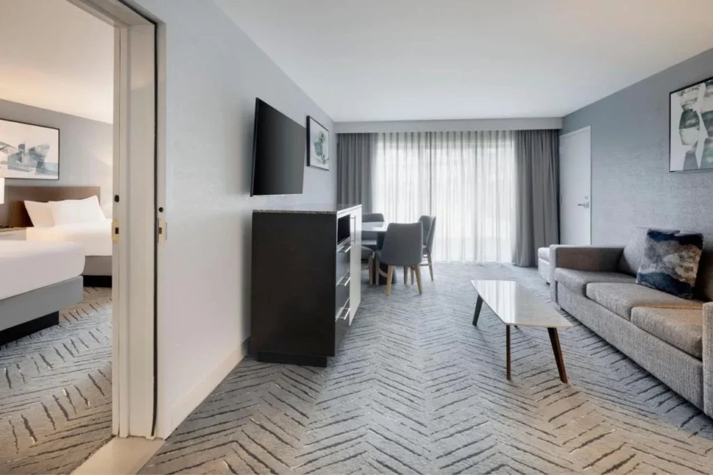 Suite living area with a sofa, dining table and separate bedroom at Delta Hotels Orlando Celebration