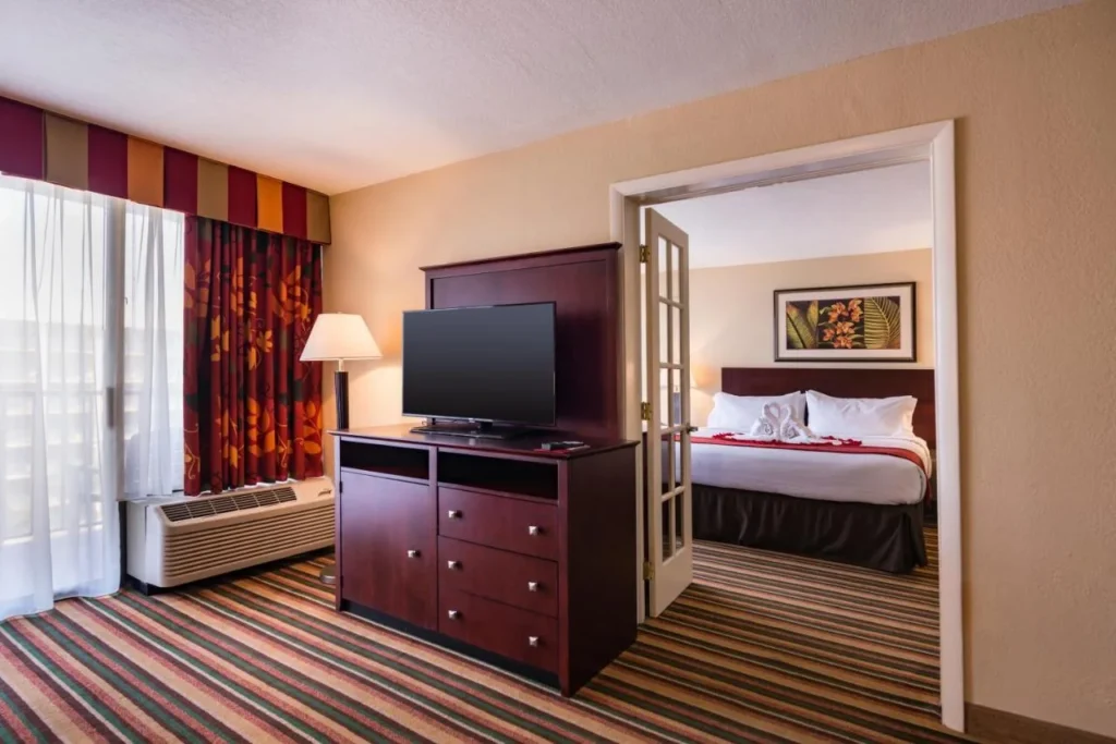 Suite sala de estar con TV y puertas francesas al dormitorio, Holiday Inn SW