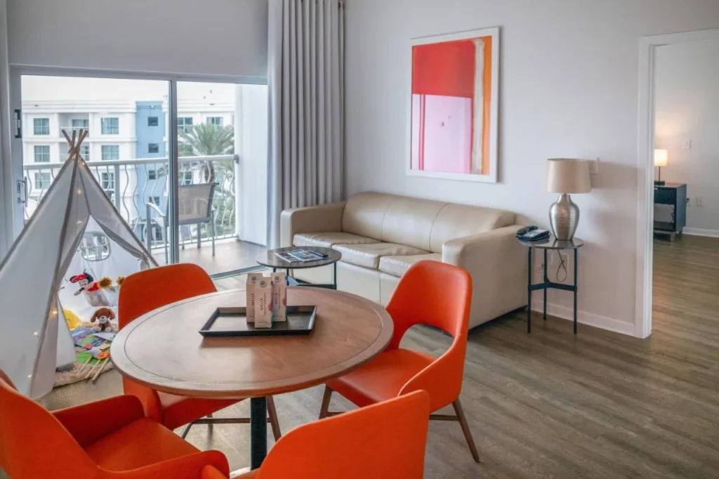 Sala de estar de la suite con sillas naranjas y una tienda de juegos para niños en Meliá Orlando Celebration