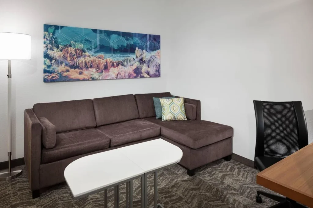 Suite living area with sectional sofa, desk chair and ocean art at SpringHill Suites at SeaWorld
