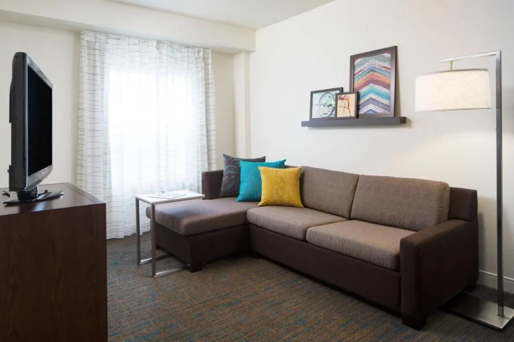 Suite con sofá seccional, lámpara de pie y TV en el Residence Inn Orlando at SeaWorld