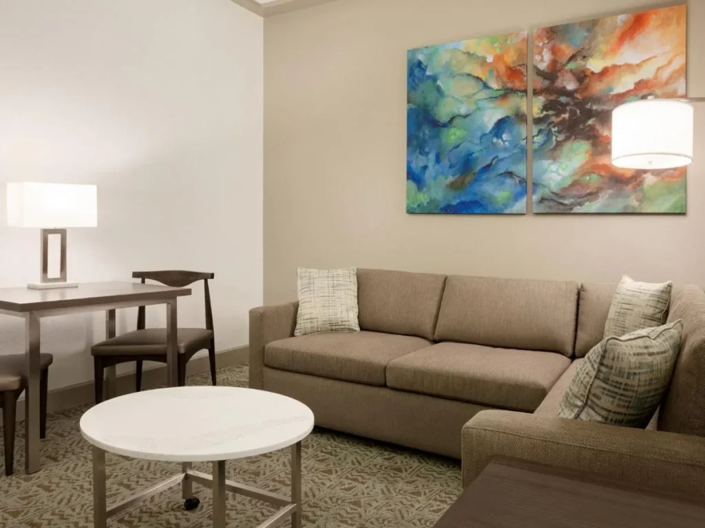 Sala de estar de la suite con sofá seccional, mesa de centro redonda y mesa de comedor, Buena Vista Suites