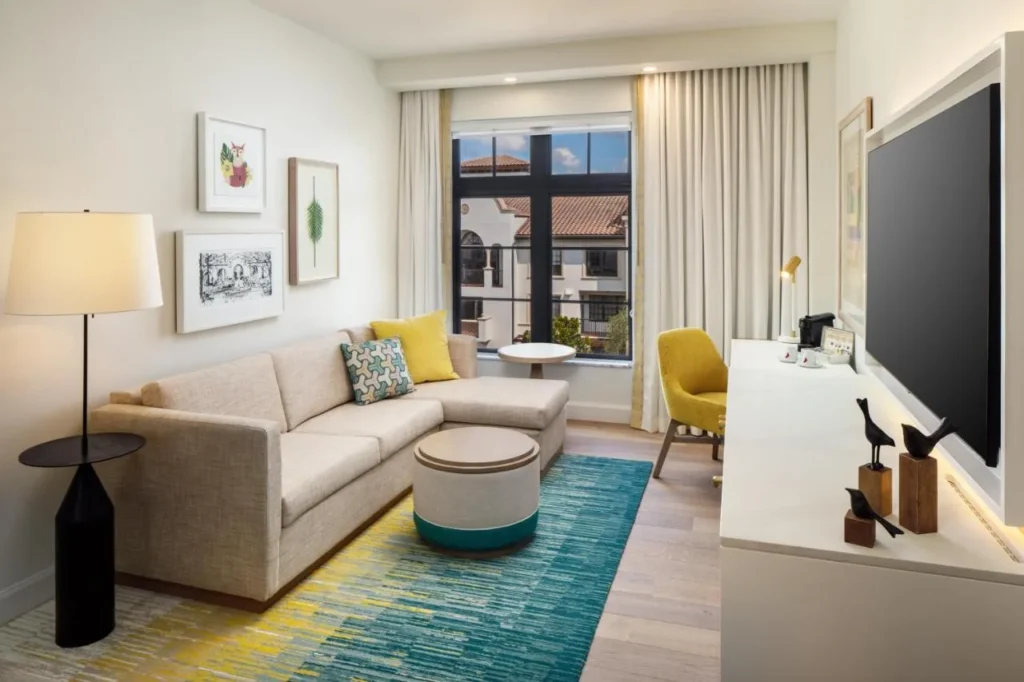 Suite living area with sectional sofa, wall TV and large window at The Alfond Inn