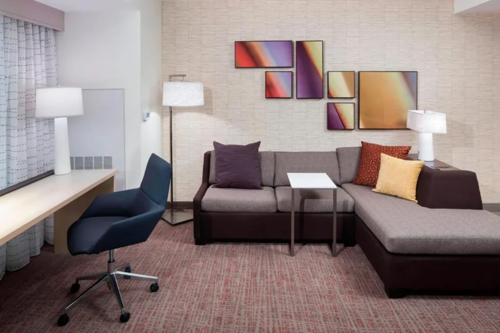 Sala de estar de la suite con sof&aacute; seccional, escritorio y arte abstracto en Residence Inn Near Universal