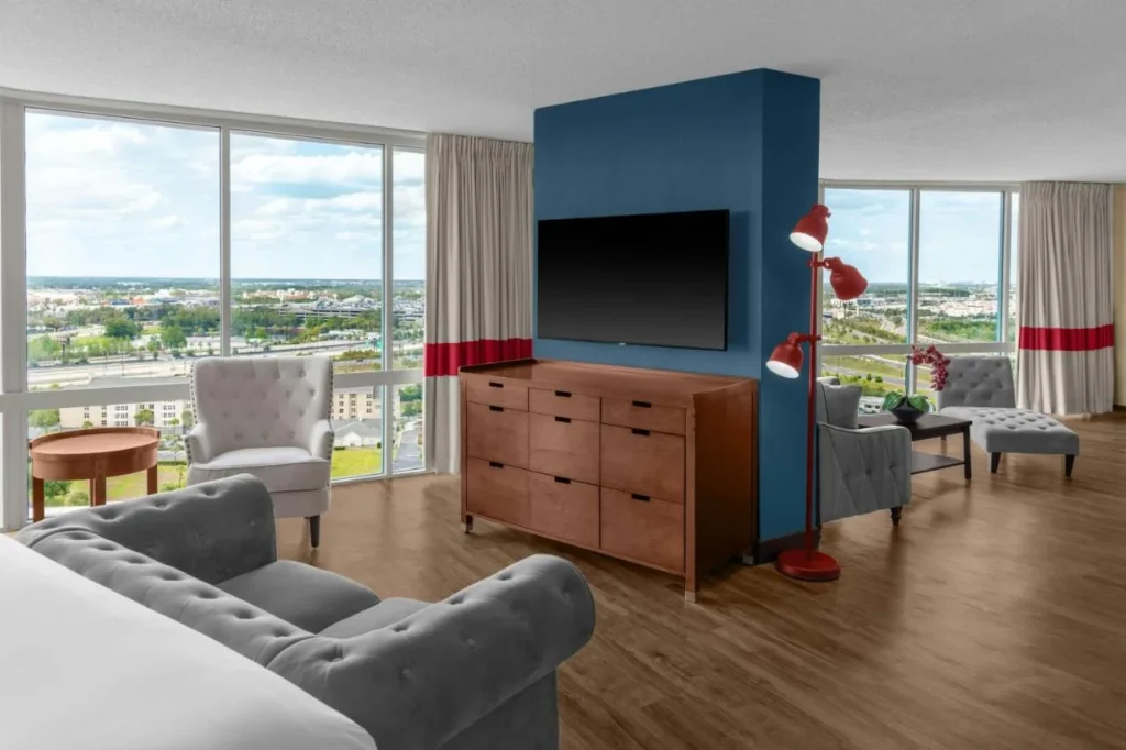 Suite living area with sofa, armchairs and floor-to-ceiling windows at Four Points Orlando International Drive