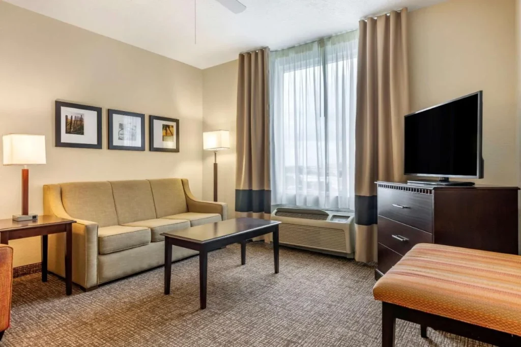 Sala de estar de la suite con sofá, mesa de centro y TV en Comfort Suites Maingate East