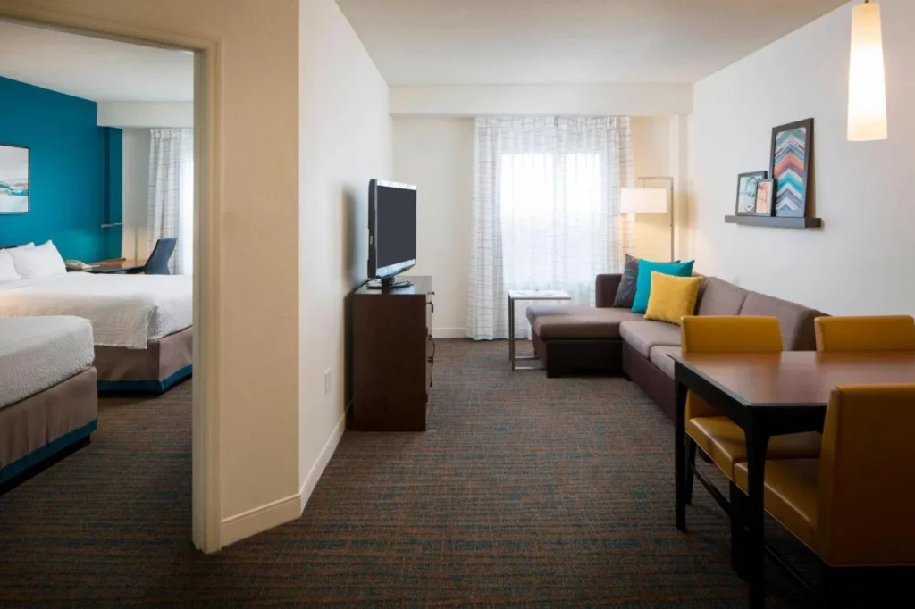 Sala de estar de la suite con sofá, mesa de comedor y vista al dormitorio en el Residence Inn Orlando at SeaWorld