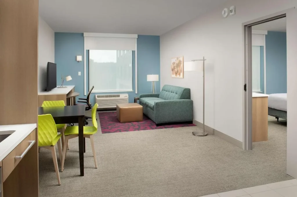 Suite living area with sofa, dining table and separate bedroom at Home2 Suites Orlando Downtown