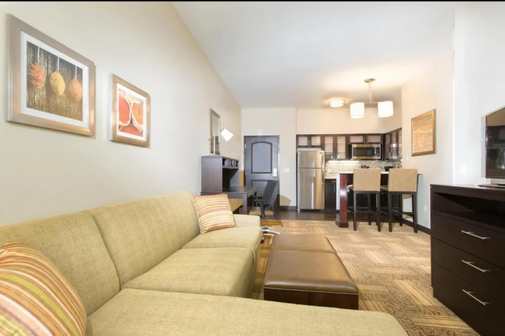 Sala de estar de la suite con sofá, otomana y barra de cocina en Staybridge Suites Orlando at SeaWorld