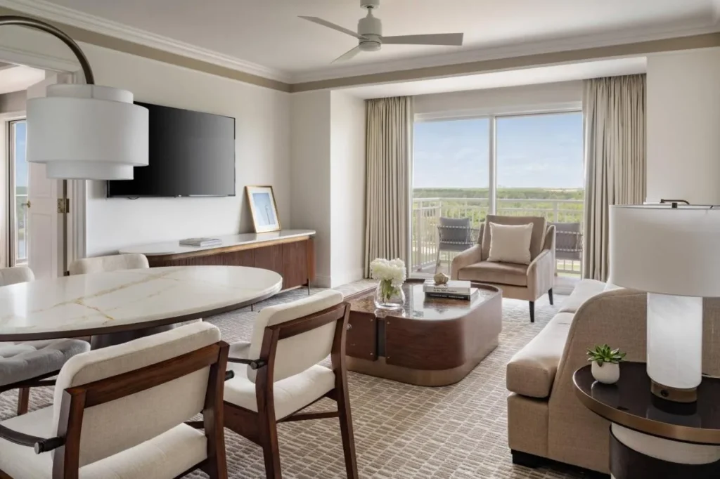 Suite con mesa de comedor, sofá y balcón en el Ritz-Carlton Orlando, Grande Lakes