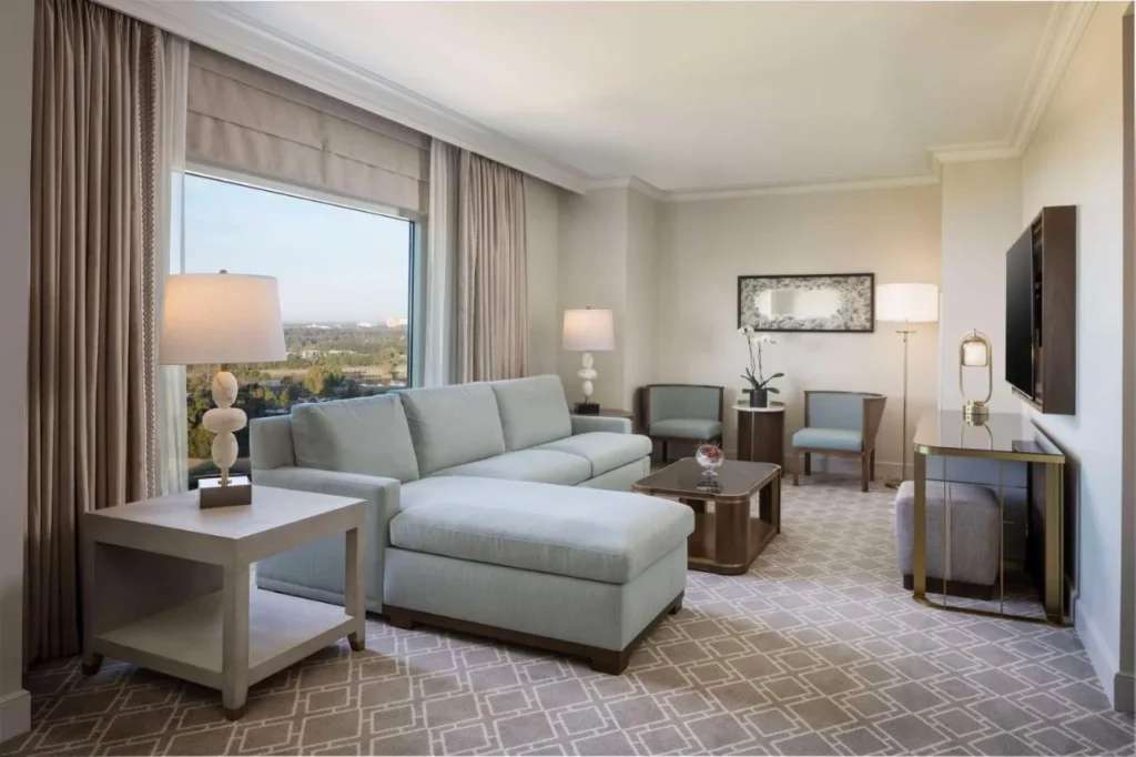 Suite living room with a high-floor window view over trees at Waldorf Astoria Orlando
