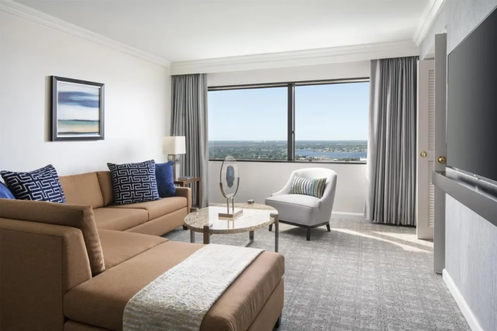 Sala de estar suite con un sof&aacute; seccional y una vista de la ventana del piso alto en Hyatt Regency Orlando