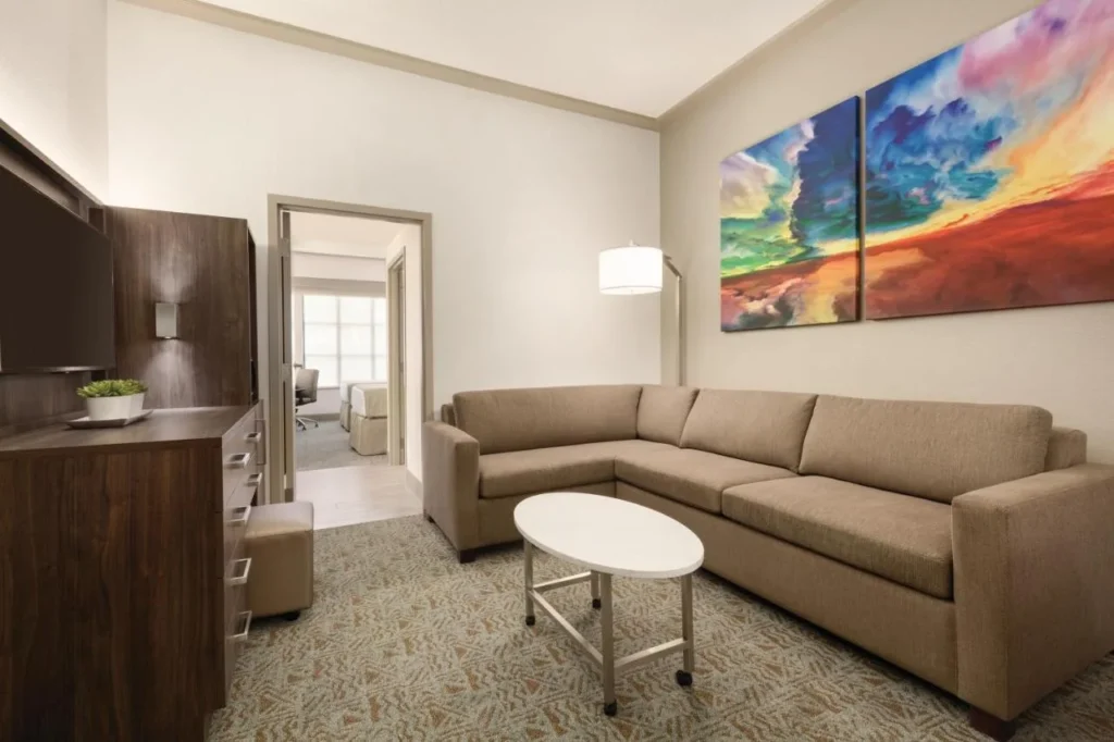 Sala de estar de la suite con un sof&aacute; seccional y puerta del dormitorio en Buena Vista Suites