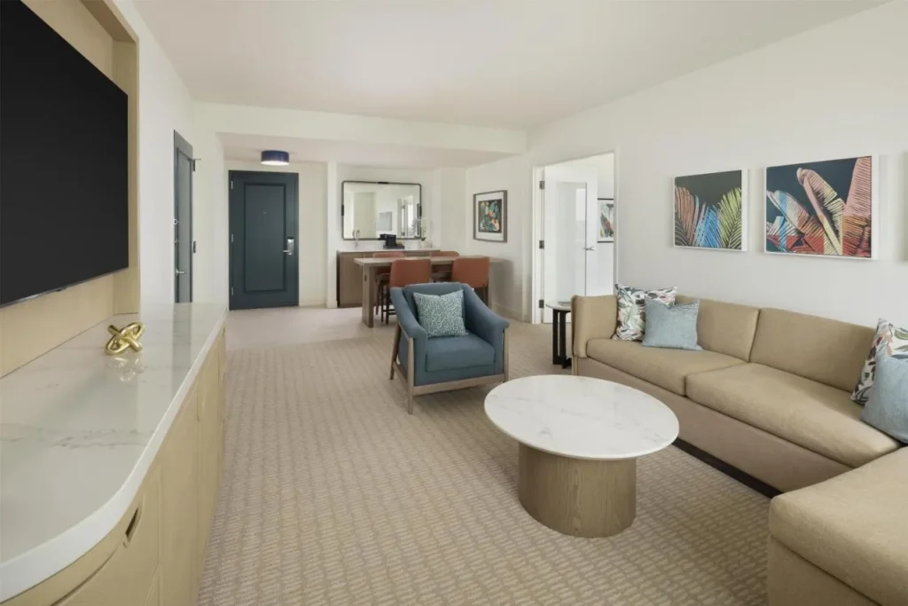 Suite living room with a sectional sofa, wall TV and dining table at Hilton Orlando