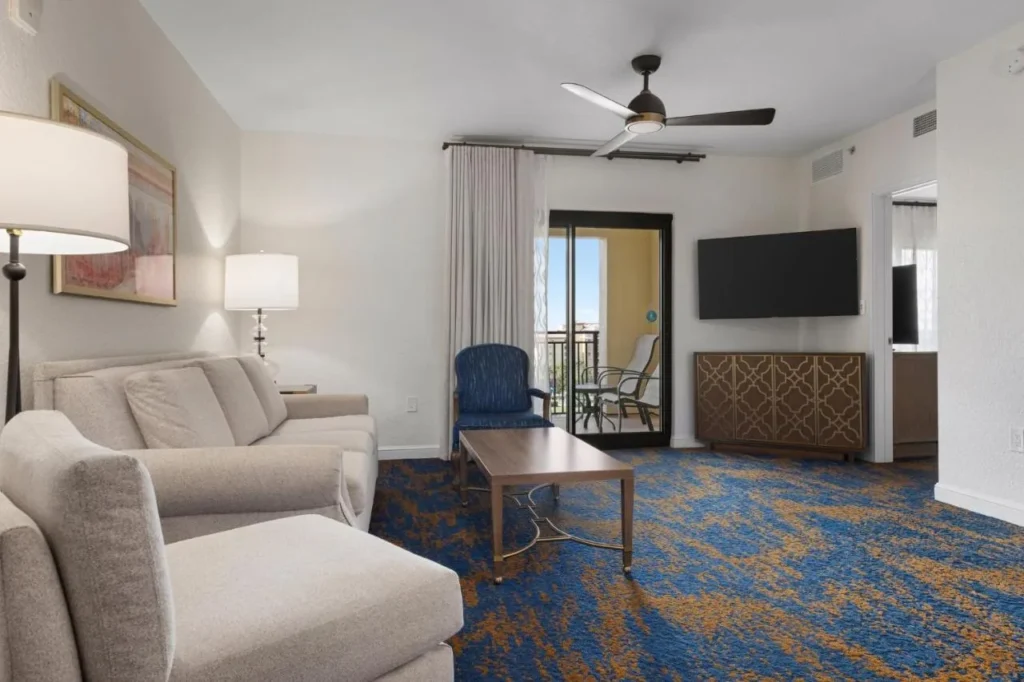 Sala de estar de la suite con sofá, sillón, TV y puerta al balcón en Club Wyndham Bonnet Creek