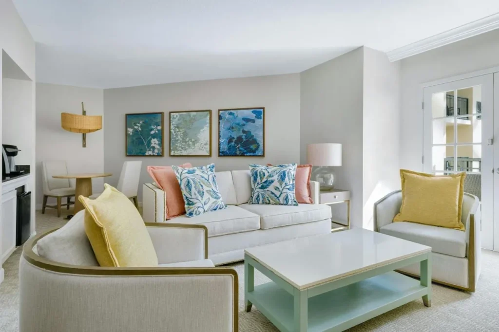 Sala de estar suite con sofá, sillones, mesa de comedor pequeña y puertas francesas en Gaylord Palms