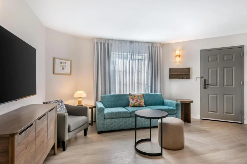 Sala de estar de la suite con un sofá de color verde azulado y TV en Sonesta ES Suites Lake Buena Vista