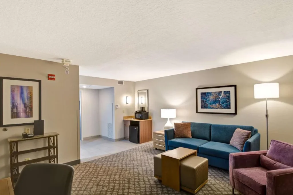 Suite living room with blue sofa, purple armchair and wet bar, Embassy Suites Orlando Downtown