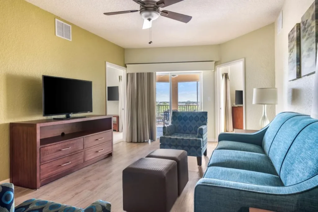 Suite con sofá azul, TV y balcón en el Hilton Vacation Club Mystic Dunes Orlando