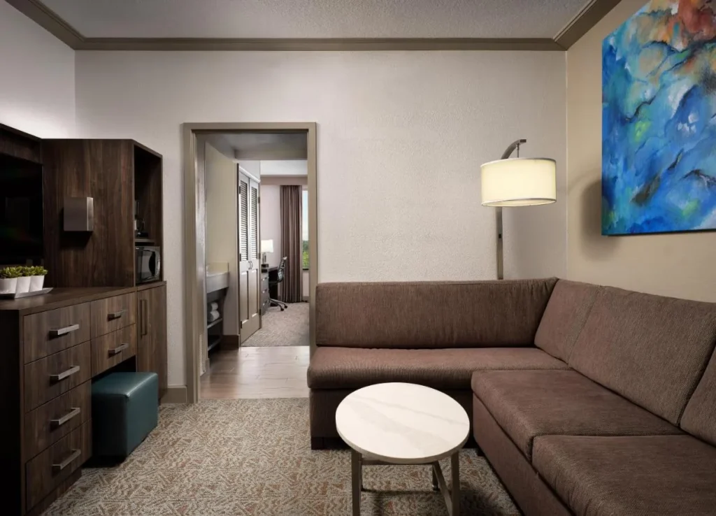 Sala de estar de la suite con sofá seccional marrón y puerta al dormitorio, Buena Vista Suites