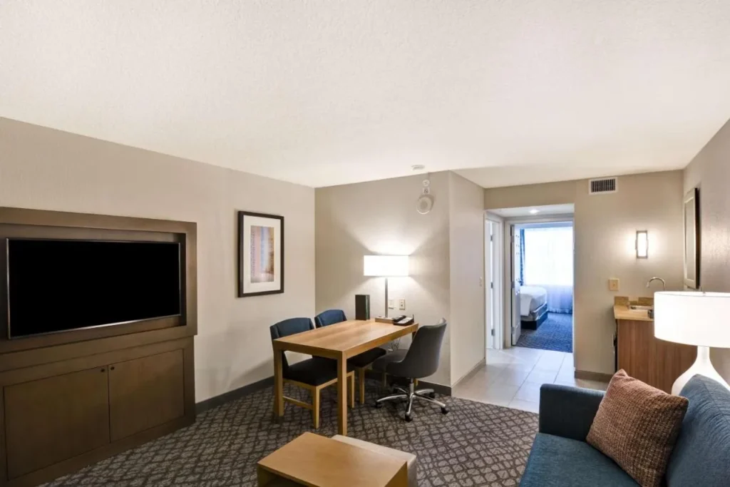 Suite living room with desk, TV and sofa at Embassy Suites Orlando Downtown