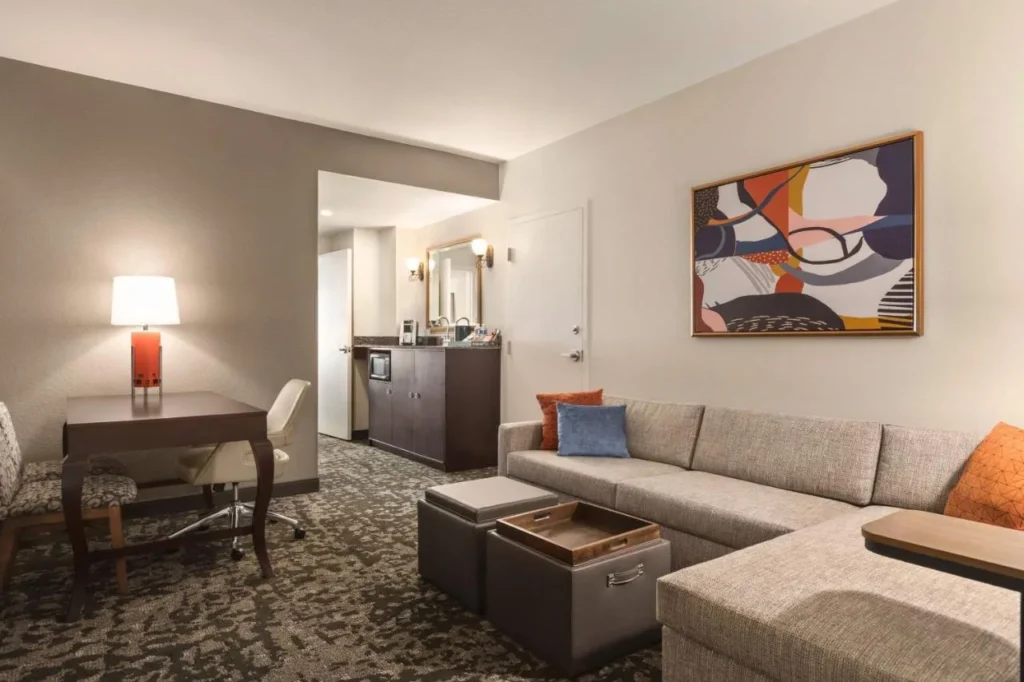 Sala de estar con sofá seccional y escritorio en Embassy Suites Lake Buena Vista South