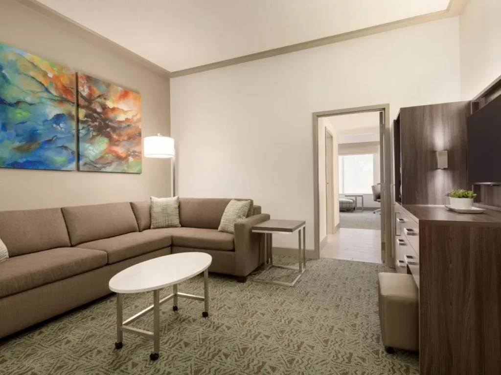 Sala de estar con sofá seccional y puerta abierta al dormitorio en Buena Vista Suites