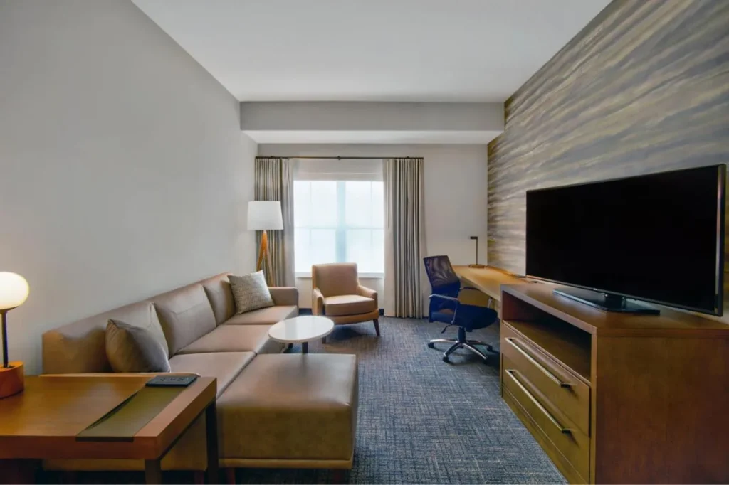 Sala de estar con sof&aacute; seccional, sill&oacute;n, escritorio y TV en el Residence Inn Flamingo Crossings