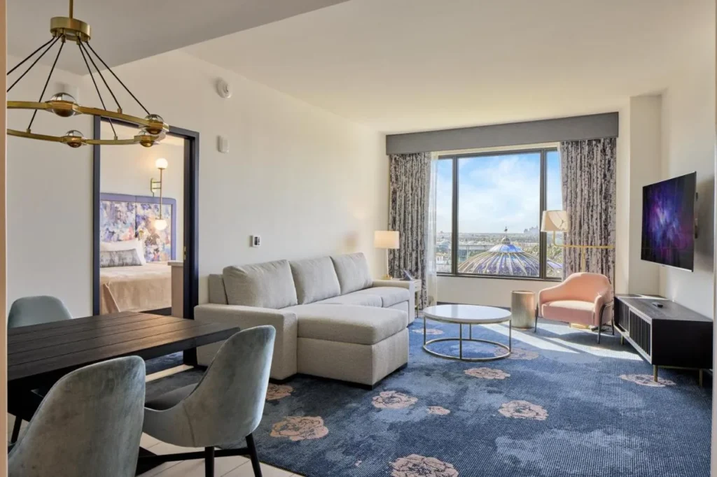 Sala de estar suite con sof&aacute; seccional, mesa de comedor y ventana grande en Universal Helios Grand Hotel