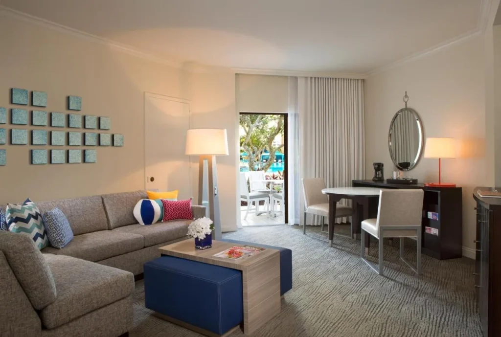 Suite living room with sectional sofa, dining table and patio door at Hilton Buena Vista Palace