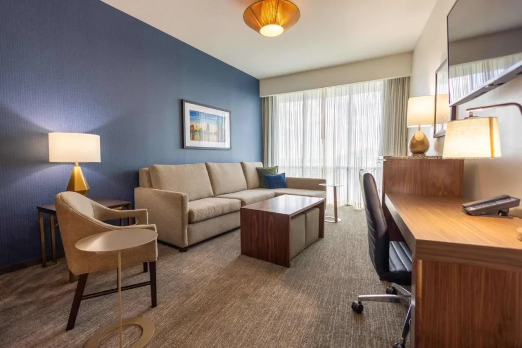 Sala de estar con sofá, sillón y escritorio en Drury Plaza Hotel Orlando Disney Springs Área