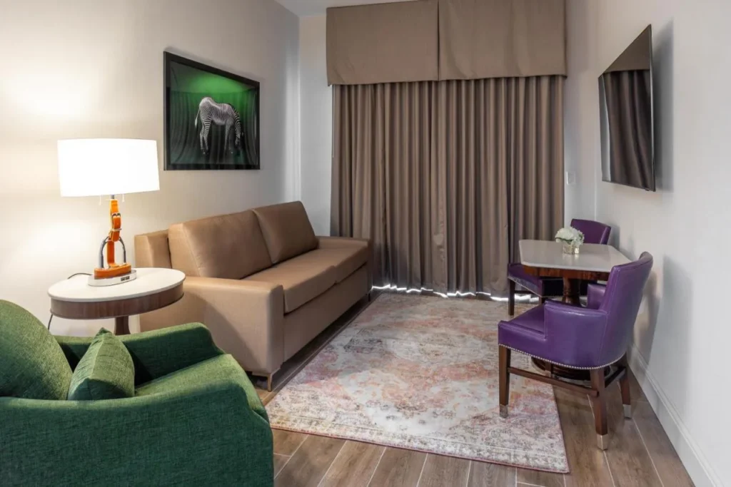 Sala de estar con sof&aacute; cama y sillas de comedor moradas en The Riding Academy Hotel